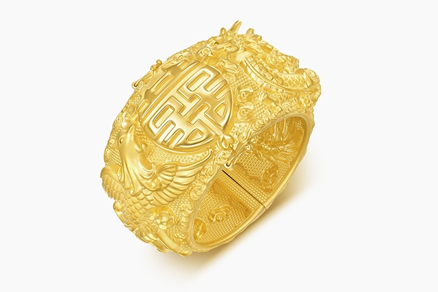 周生生「生生有囍・龍鳳篇」999.9黃金手鐲展示（約0.869兩，HK$32,702），採用硬金電鑄工藝，浮雕刻劃龍飛鳳舞造型，祥龍瑞鳳盤繞「囍」字，寓意龍鳳呈祥與佳偶天成，適合婚禮佩戴與送禮。
